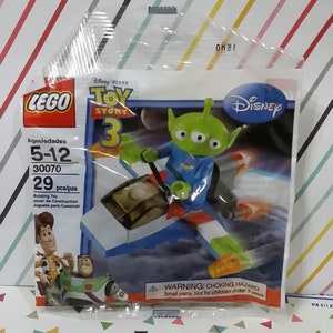 Puede incluir: Set de construcci&oacute;n LEGO Toy Story 3 con un personaje extraterrestre verde de tres ojos montando una nave espacial. El set incluye 29 piezas y se recomienda para ni&ntilde;os de 5 a 12 a&ntilde;os. El embalaje presenta el logotipo de Disney y el logotipo de Toy Story 3.