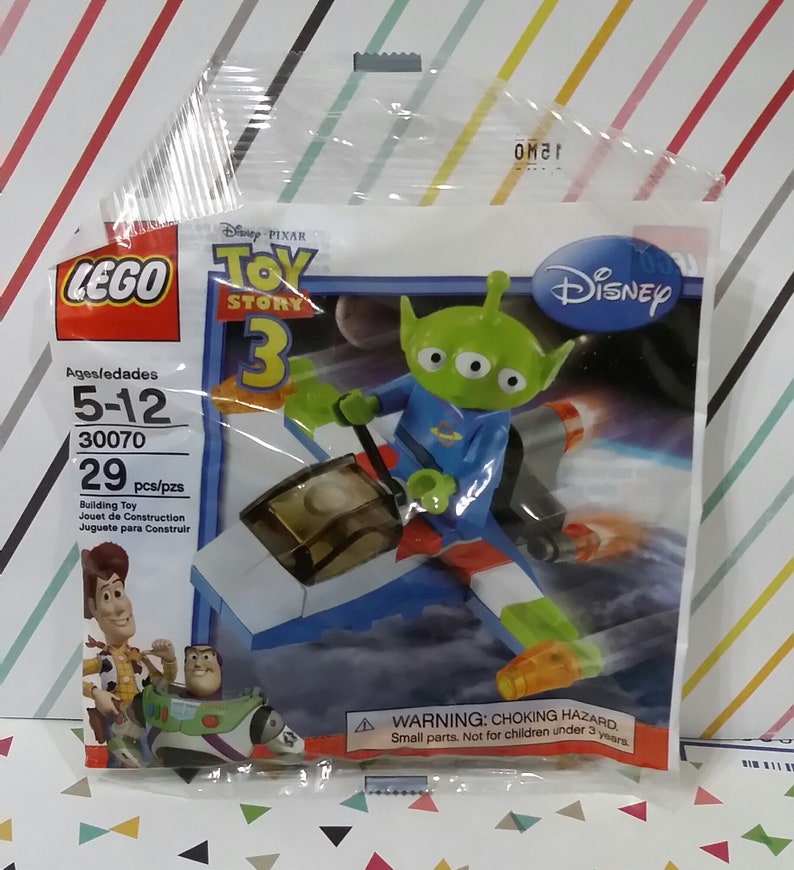 Puede incluir: Set de construcci&oacute;n LEGO Toy Story 3 con un personaje extraterrestre verde de tres ojos montando una nave espacial. El set incluye 29 piezas y se recomienda para ni&ntilde;os de 5 a 12 a&ntilde;os. El embalaje presenta el logotipo de Disney y el logotipo de Toy Story 3.