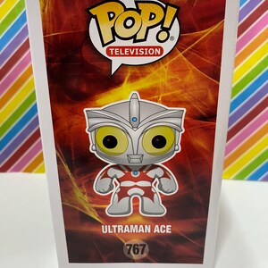 以下が含まれることがあります： ウルトラマンエースのFunko Pop! Televisionボックス。ボックスは赤と白の配色で、キャラクターの画像が大きく表示されています。Pop!のロゴが上部にあり、番号767が下部にあります。