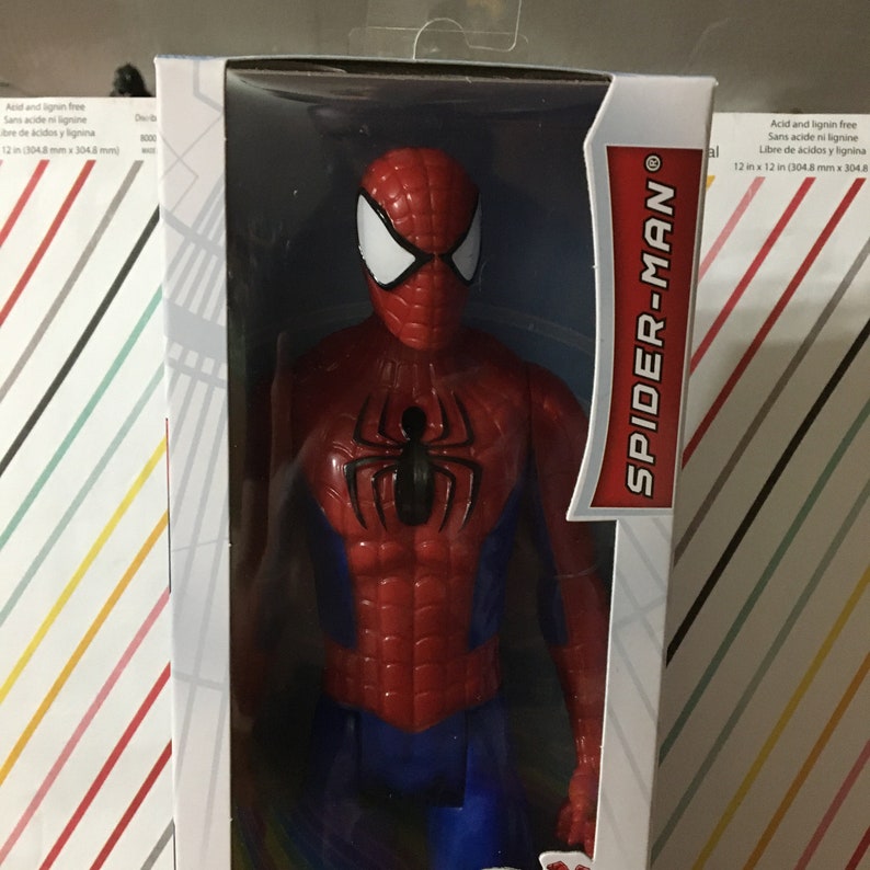 May include: A red and blue action figure of Spider-Man in a plastic package. The figure is 12 inches tall and has a black spider logo on the chest. The packaging has the words "SPIDER-MAN" in red letters.