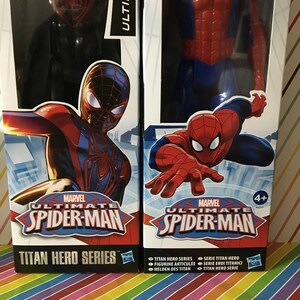 May include: Two action figures from the Marvel Ultimate Spider-Man Titan Hero Series. The figures are packaged in cardboard boxes with red, blue, and black designs. The boxes feature the Marvel logo and the text "Ultimate Spider-Man" and "Titan Hero Series".