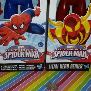 May include: Two action figure boxes featuring Marvel's Ultimate Spider-Man. The boxes are red and blue with images of Spider-Man in different poses. The text on the boxes reads "Marvel Ultimate Spider-Man" and "Titan Hero Series".