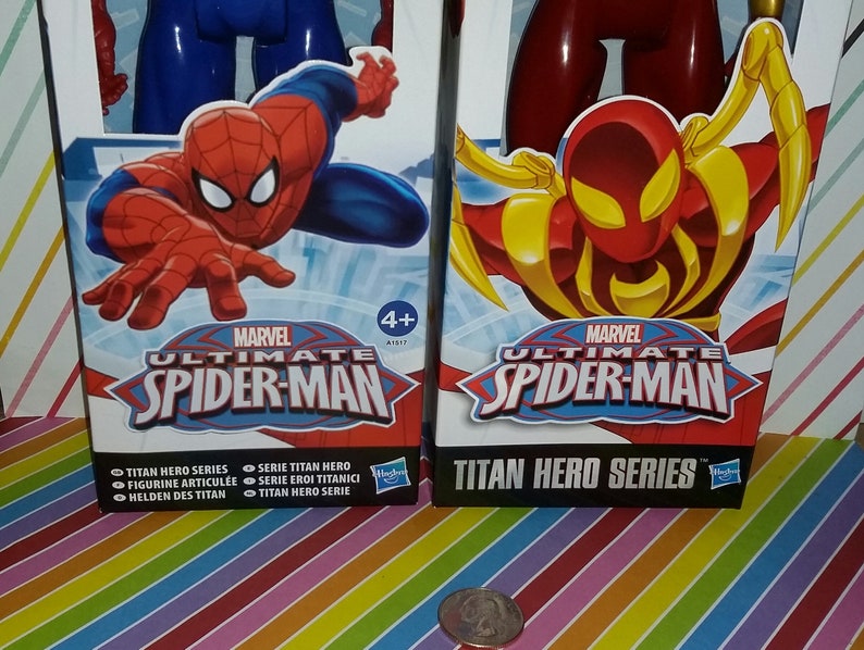 May include: Two action figure boxes featuring Marvel's Ultimate Spider-Man. The boxes are red and blue with images of Spider-Man in different poses. The text on the boxes reads "Marvel Ultimate Spider-Man" and "Titan Hero Series".