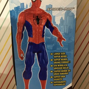 May include: A red and blue Spider-Man action figure with a large size super hero written on the box. The figure is standing in front of a city skyline.