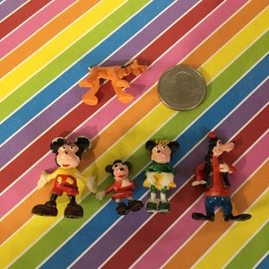 May include: A set of six small plastic figurines of Disney characters. The characters include Mickey Mouse, Minnie Mouse, Donald Duck, Goofy, Pluto, and a smaller Mickey Mouse. The figurines are all in various poses and are painted in bright colors.