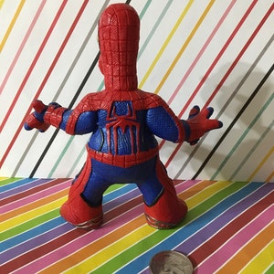 Peut inclure: Une figurine d'action en plastique rouge et bleue de Spider-Man. La figurine est debout, les bras tendus. La figurine mesure environ 12,5 cm de haut.