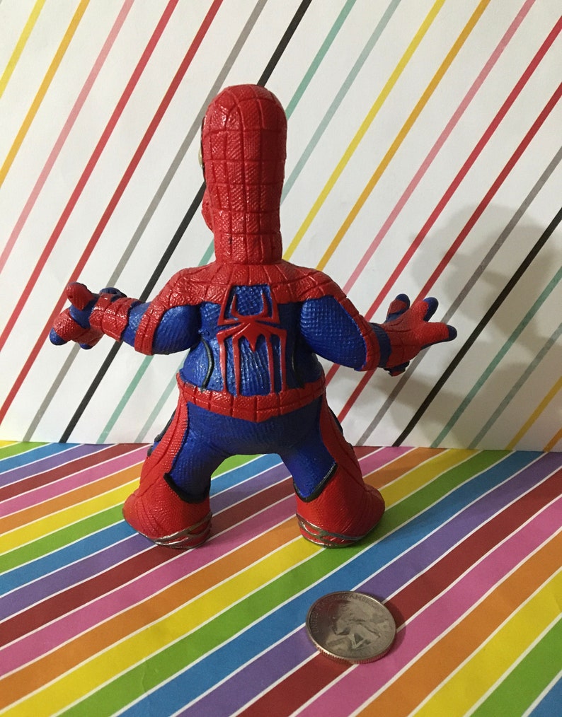 Peut inclure: Une figurine d'action en plastique rouge et bleue de Spider-Man. La figurine est debout, les bras tendus. La figurine mesure environ 12,5 cm de haut.