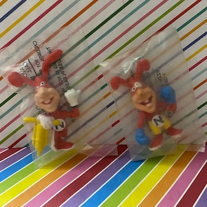 May include: Two red cartoon rabbit figurines in plastic packaging. One rabbit is holding a yellow drill and the other is wearing blue boxing gloves. The rabbit with the drill has a yellow number "1" on its chest and the rabbit with the boxing gloves has a yellow number "2" on its chest.