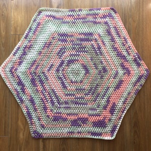May include: A hexagonal crochet blanket with a spiral pattern in shades of pink, green, and purple.