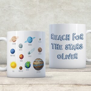 Pu&ograve; includere: Tazza in ceramica bianca con un contorno blu dei pianeti del nostro sistema solare e il testo "REACH FOR THE STARS OLIVER" sull'altro lato.