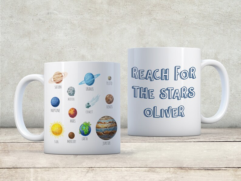 Pu&ograve; includere: Tazza in ceramica bianca con un contorno blu dei pianeti del nostro sistema solare e il testo "REACH FOR THE STARS OLIVER" sull'altro lato.