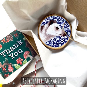 May include: A white polar bear painted on a round wooden disc with a blue background and white polka dots. The disc is packaged in white tissue paper with a thank you card that says 'Thank You' in green text on a green background with red berries and a brown bear.