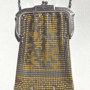 May include: Vintage silver mesh purse with a chain handle. The purse features a silver frame and a body of silver and yellow metal mesh. The bottom edge has a scalloped design. A classic accessory.