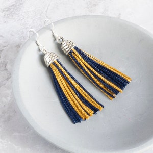 navy and yellow tassel earrings laying on a dish