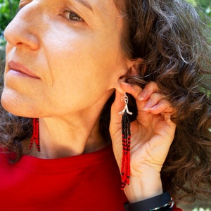 woman wearing hockey charm earrings with long beaded tassels