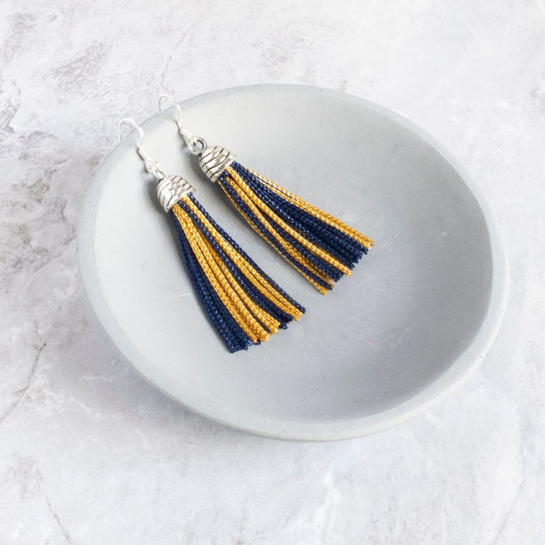 navy and yellow tassel earrings laying on a dish