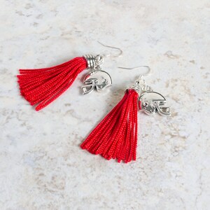 May include: A pair of red tassel earrings with silver football helmet charms.