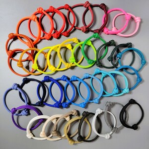 May include: A collection of adjustable cord bracelets in a wide variety of colors including neon pink, orange, yellow, green, blue, purple, black, white, beige, and brown. Each bracelet features a simple sliding knot closure mechanism.