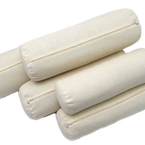 May include: Four cream-colored cylindrical pillows with zippers. The pillows are stacked on top of each other.