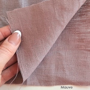May include: A close-up of a mauve-colored linen fabric. The fabric has a textured weave and is folded in half.