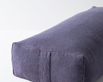 May include: A rectangular purple meditation cushion with a textured fabric cover.
