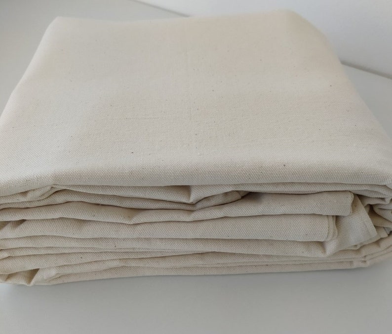 Op de afbeelding: Een stapel gevouwen natuurlijke canvas stof.