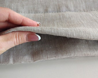 May include: Close-up of a beige linen fabric folded in half, showing the raw edge of the fabric.