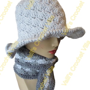 May include: A gray crocheted hat with a wide brim and a matching gray crocheted scarf. The hat and scarf are made with a textured stitch pattern.