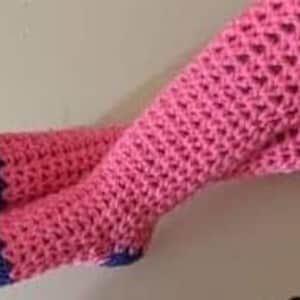 Puede incluir: Un par de calcetines de punto de ganchillo de color rosa y morado, hasta la rodilla, con un patrón texturizado.