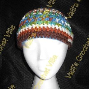 May include: A crocheted hat with a brown, white, and blue color scheme. The hat is on a white mannequin head. The text "Valli's Crochet Villa" is visible on the image.