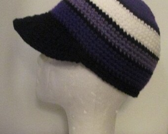 Puede incluir: Un gorro de punto de color morado, blanco y negro con una visera negra.