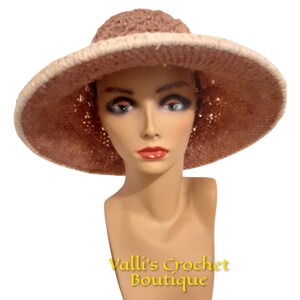May include: A pink crocheted sun hat with a white trim. The hat is on a mannequin head.