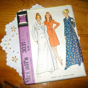 May include: A vintage McCall's sewing pattern, number 3031, for Misses' and Women's robes. The pattern envelope features illustrations of three robe designs in white, orange, and blue floral patterns. The size is 12-14, bust 34-36 inches.