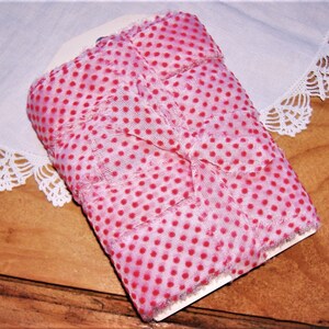 May include: A roll of pink and white polka dot fabric ribbon with frayed edges. The ribbon is folded and tied in a bow.