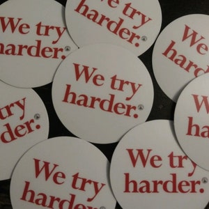 May include: Multiple white round stickers with the text "We try harder." printed in red.