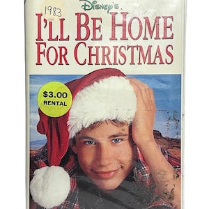 May include: A VHS tape of Disney's I'll Be Home For Christmas starring Jonathan Taylor Thomas. The cover features a person wearing a red and white Santa hat and a plaid shirt. Text includes the title, actor name, and Somewhere between L.A. and N.Y.