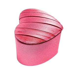 May include: A pink heart-shaped jewelry box with a satin-like finish.