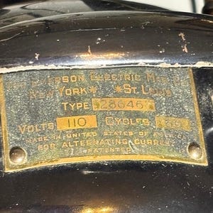 May include: Close-up of a vintage metal plate with text. The plate is attached to a black surface. Text includes "Jefferson Electric Mfg. New York, St. Louis, Type 28646, Volts 110, Cycles 60, Made in United States of America for Alternating Current, Patented."