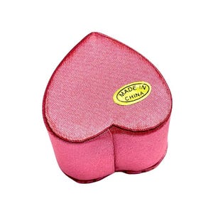 May include: A pink heart-shaped velvet jewelry box with a gold label that reads "MADE IN CHINA".