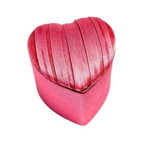 May include: A pink heart-shaped jewelry box with a satin ribbon design.