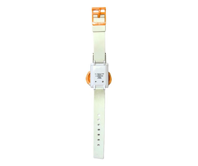 May include: A vintage digital watch with a white strap and an orange buckle. The watch face is orange and square, with a white casing. The strap has multiple holes for adjustment. The watch is a retro accessory.
