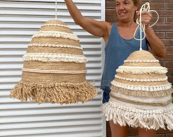 Puede incluir: Dos grandes lámparas colgantes redondas tejidas con flecos. Las lámparas están hechas de materiales naturales como el yute y tienen una combinación de colores crema y beige.