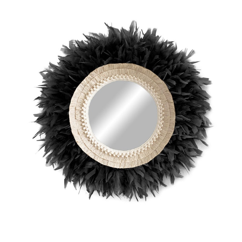 May include: A round mirror with a black feather frame and a cream-coloured woven rope border.