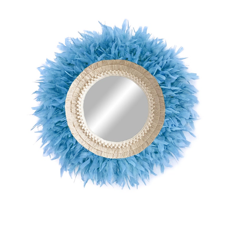 May include: A round mirror with a light blue feather trim and a cream-coloured macrame frame.