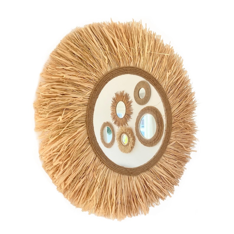 May include: A round straw mirror with a woven rope frame and multiple smaller mirrors inside. The mirror has a natural, rustic look.