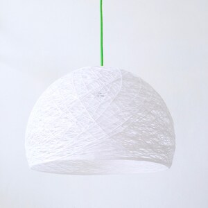 May include: A white, string-like pendant light fixture with a green cord hanging from the ceiling.