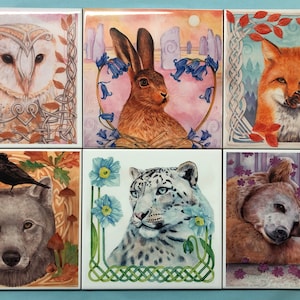 May include: Six square ceramic tiles with Celtic knotwork borders, each featuring a different animal: an owl, a hare, a fox, a wolf, a snow leopard, and a bear with a hare. The tiles are painted in a watercolour style with muted colours.