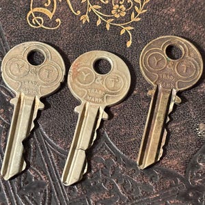 May include: Three vintage metal keys with circular bows, each featuring the embossed text Y & T and TRADE MARK. The keys have a metallic finish with varying degrees of oxidation and patina, showing distinct jagged bitting along the blade edges.