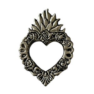 Peut inclure: Un cadre en forme de cœur argenté avec un motif floral. Le cadre est décoré de roses et d'un motif en forme de flamme en haut.