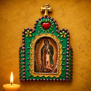 May include: A decorative wall plaque featuring a central image of the Virgin of Guadalupe framed in gold, surrounded by a green border with pink and blue dots, a red heart at the top, and a gold cross finial, set against a textured yellow wall.